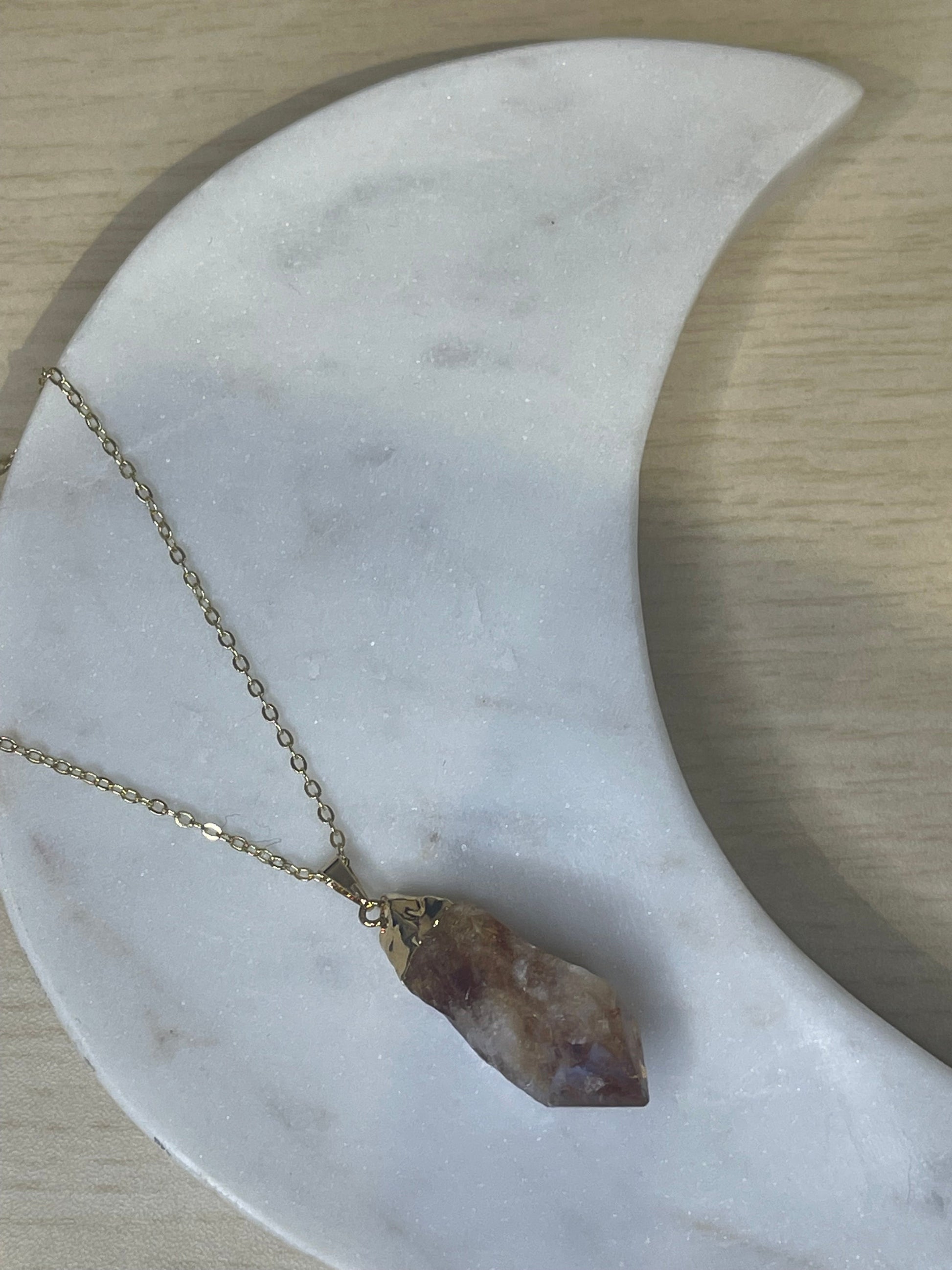Necklace with a crystal pendant on a marble surface