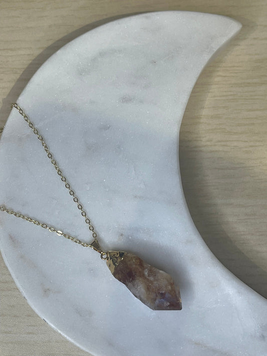 Necklace with a crystal pendant on a marble surface